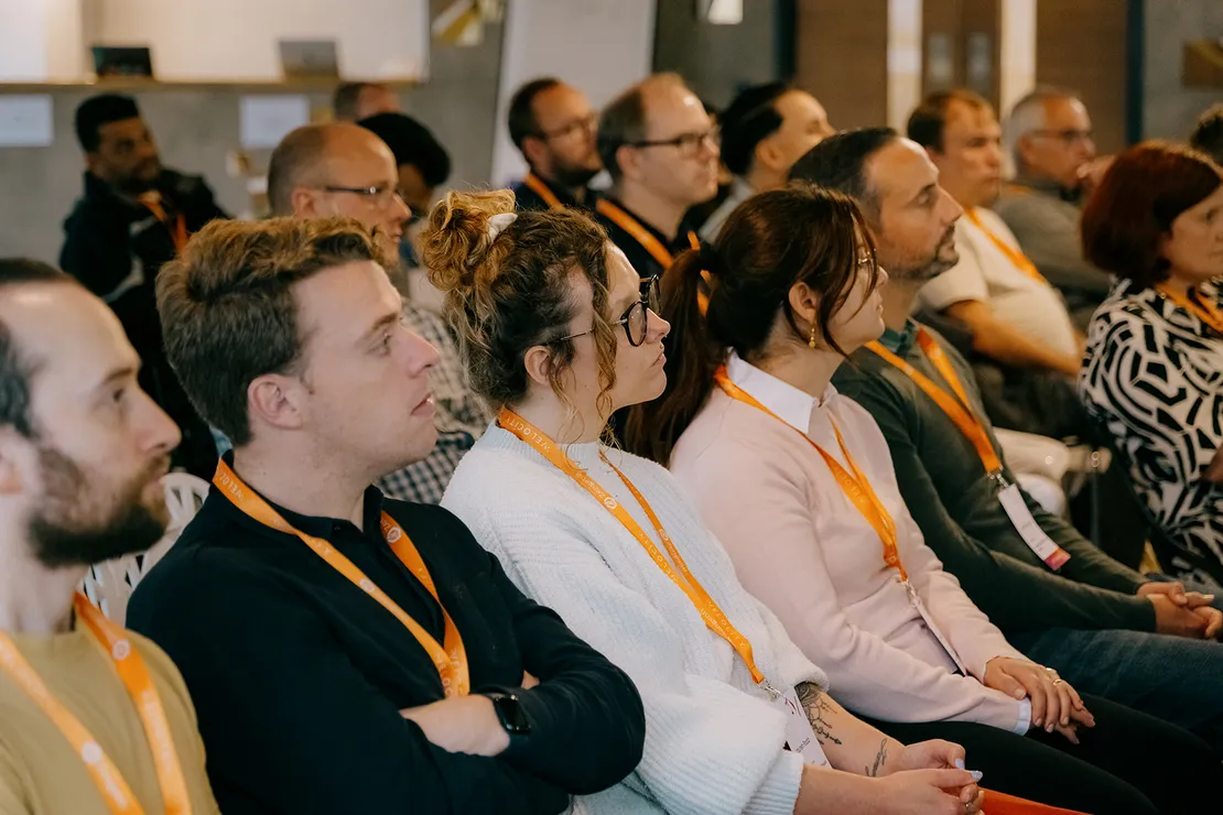 4 people sat down, listening intently to someone deliver a presentation